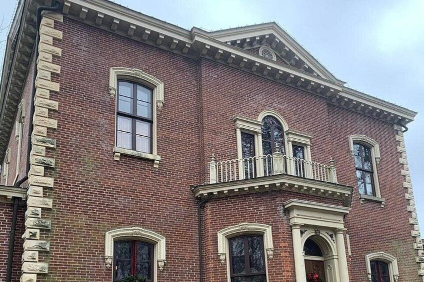 A red brick building with a balcony, arched windows, and a decorative cornice. 3