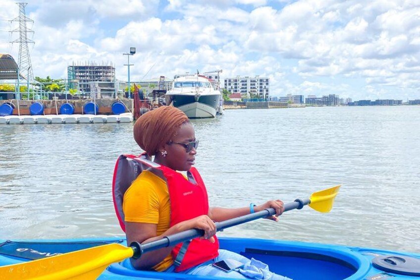 A person in a kayak on a body of water with a cityscape in the background. 4