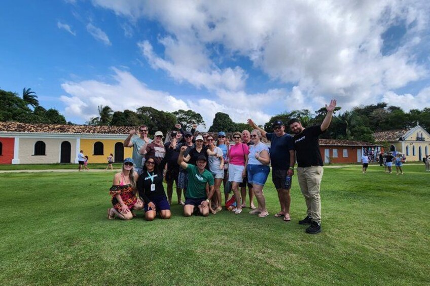 A group of people posing on a grassy field with historic buildings in the background. 3