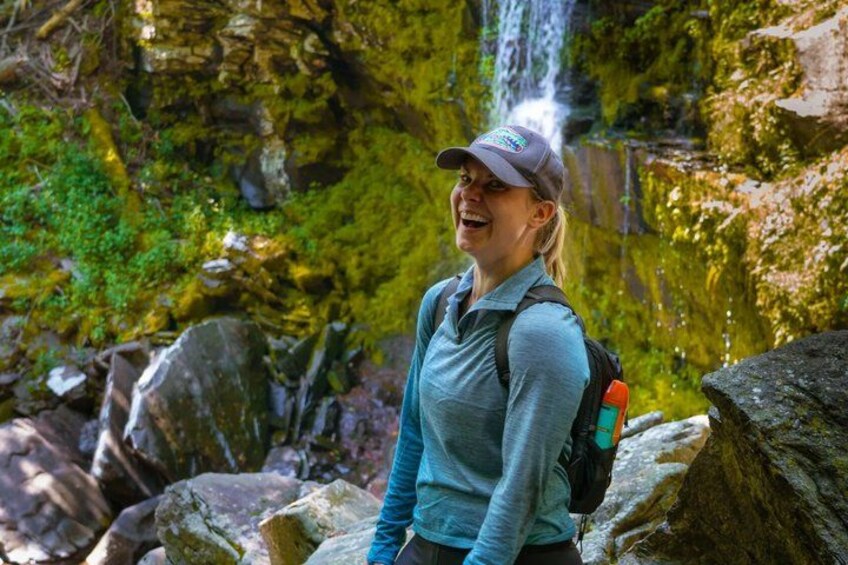 A person hiking in a rocky area with a waterfall in the background. 3