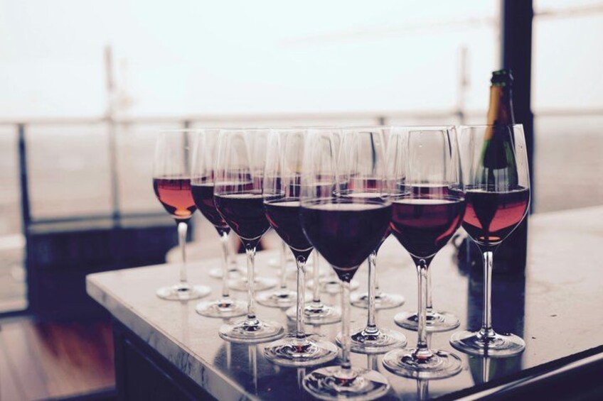 A row of wine glasses on a table with a bottle of wine in the background. 5
