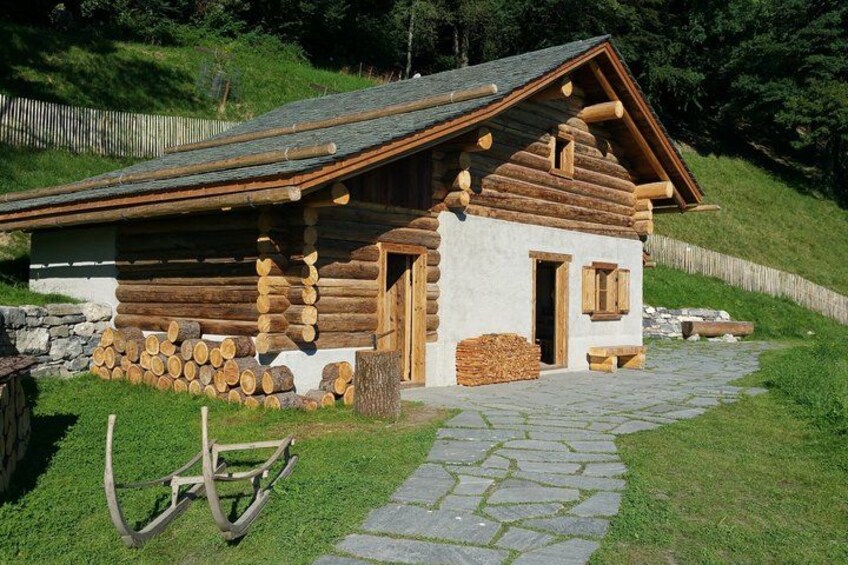 A log cabin with a stone pathway leading to it, surrounded by greenery and a wooden fence. 5