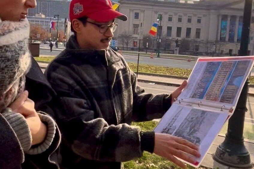 A person holding a map or directory outdoors with a building and flag in the background. 5