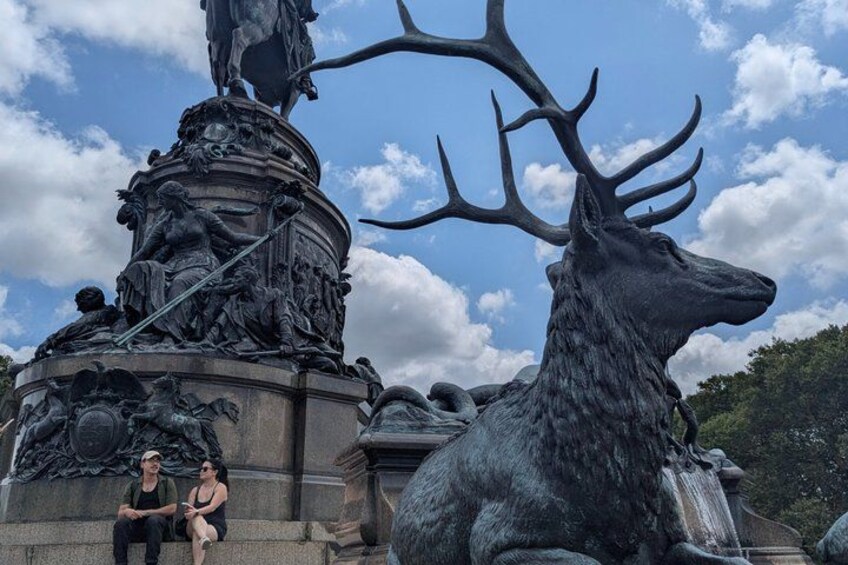A large elk statue with antlers, a smaller deer statue, and a fountain. 3