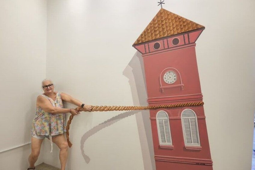 A person pulling a rope attached to a wall-mounted clock tower. 3