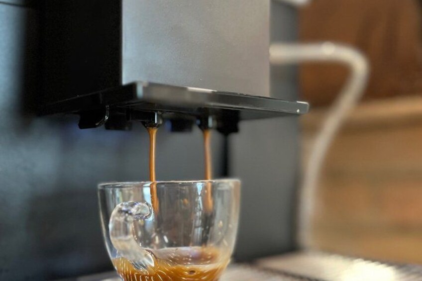 A coffee machine dispensing coffee into a glass cup. 4
