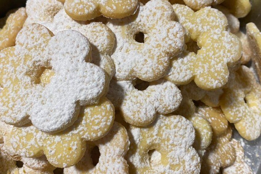 A pile of round, flower-shaped cookies dusted with powdered sugar. 5