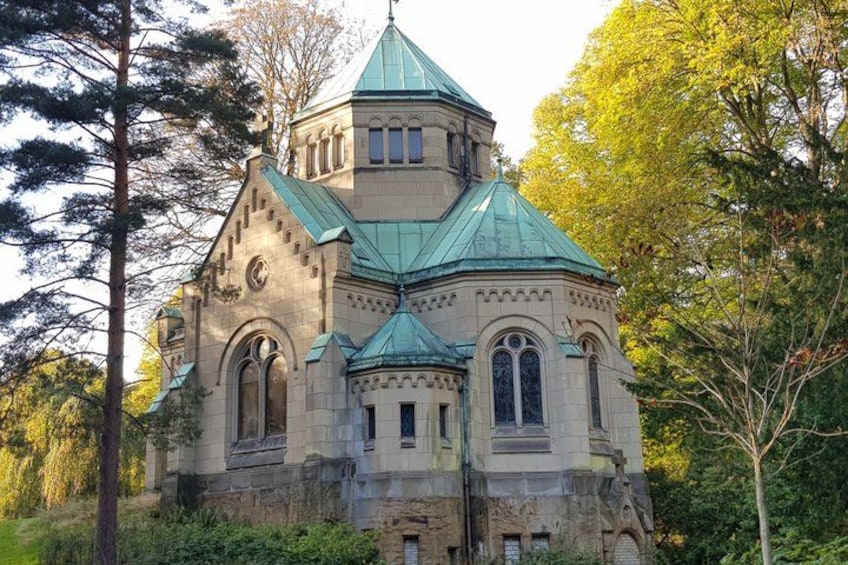 A historic building with a green roof, arched windows, and a tower. 3