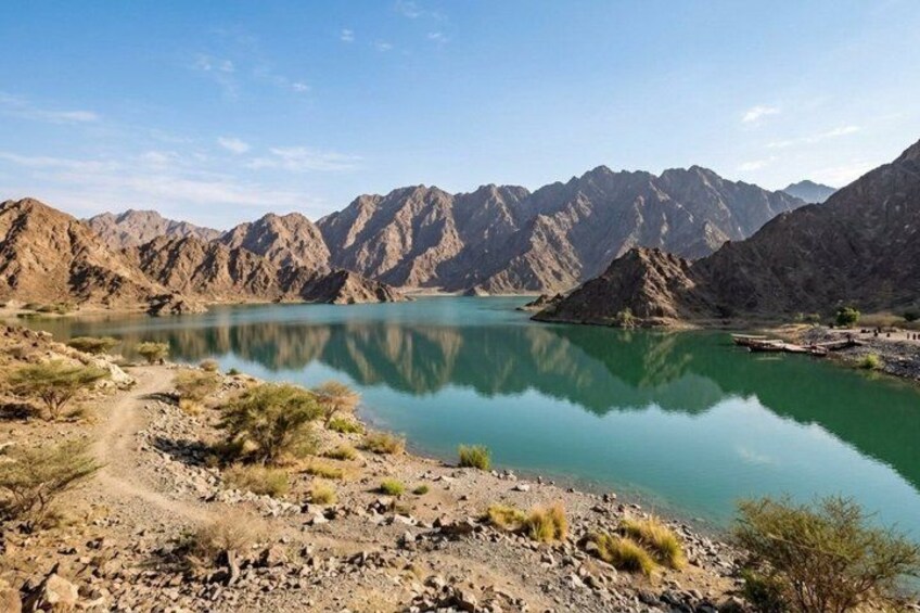 A mountainous landscape with a clear lake, rocky terrain, and sparse vegetation. 4