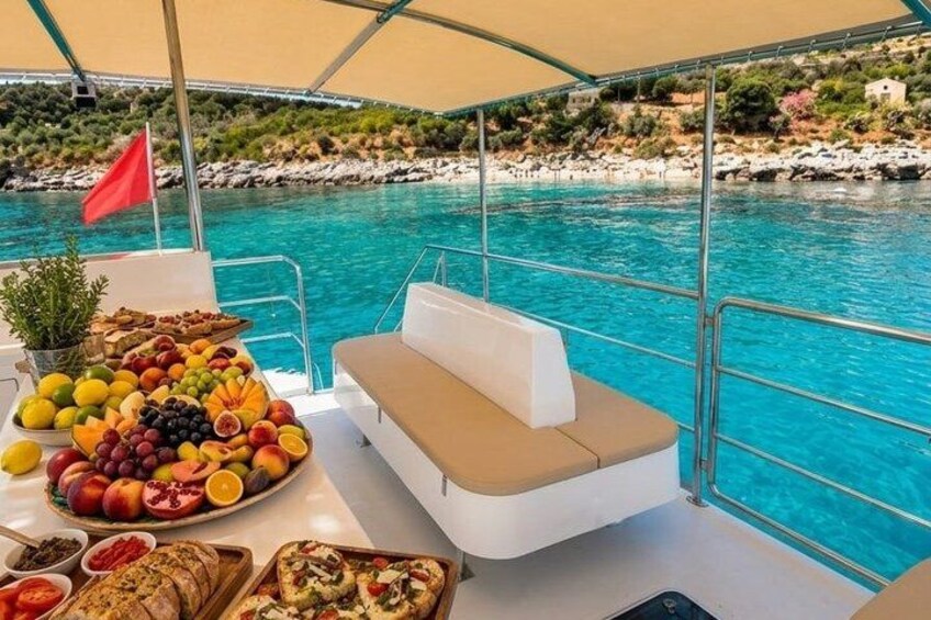 A boat with a table of fruits and vegetables, a cushion, and a view of a coastal area with rocks and a flag. 5