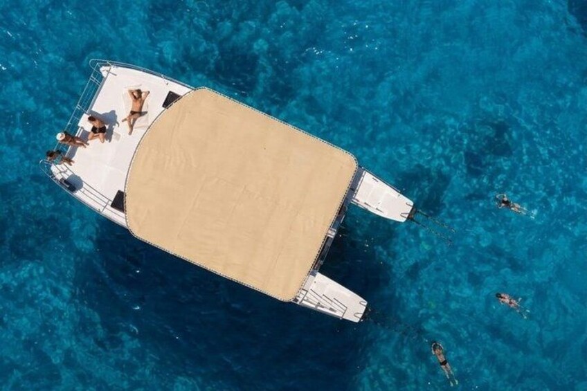 A boat with a covered deck, surrounded by clear blue water. 4