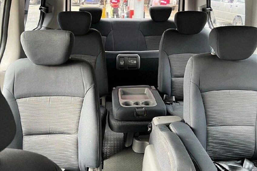 A car's interior with grey seats, a central console, and a rearview mirror. 5