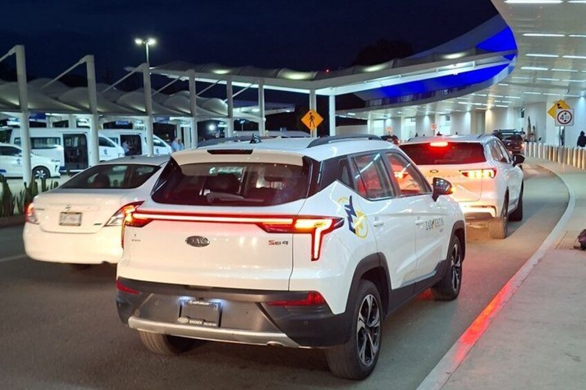 A toll booth with vehicles, including a white SUV, at night. 2