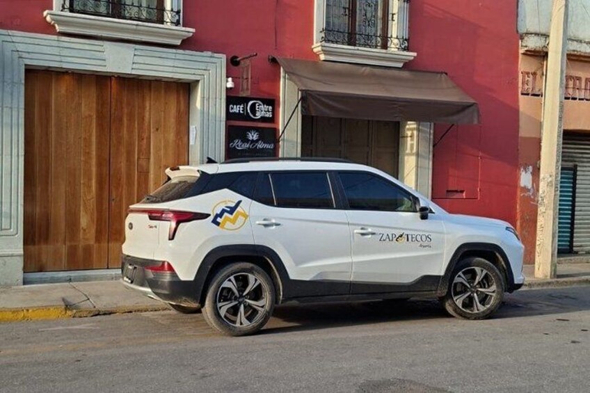 A white SUV parked in front of a building with a sign that reads 'CAFE El Rincón.' 3