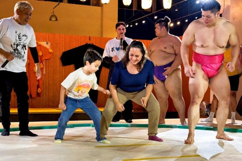 A sumo wrestling match with participants and an audience. 4
