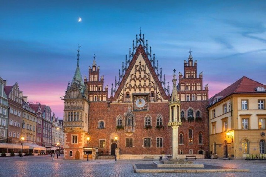 A historic building with a clock tower, arched windows, and a central tower with a pointed roof. 2