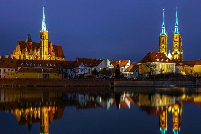 A historic cityscape with a prominent church and twin spires, reflecting in a calm river. 5
