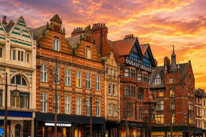 A row of historic buildings with varied architectural styles, including Tudor and Georgian designs, under a sunset sky. 2