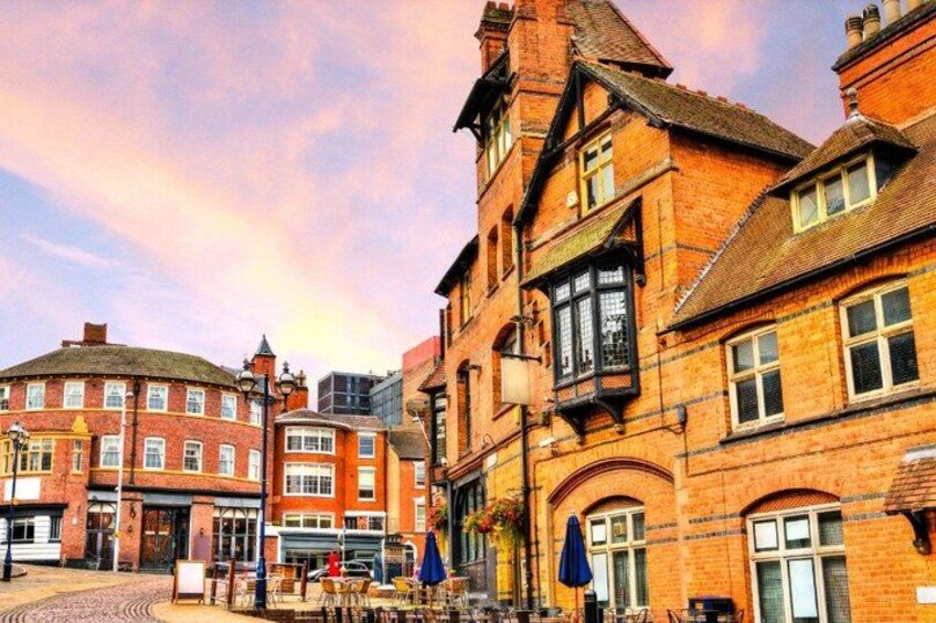 A street with red brick buildings, a cobblestone street, and outdoor seating areas. 3