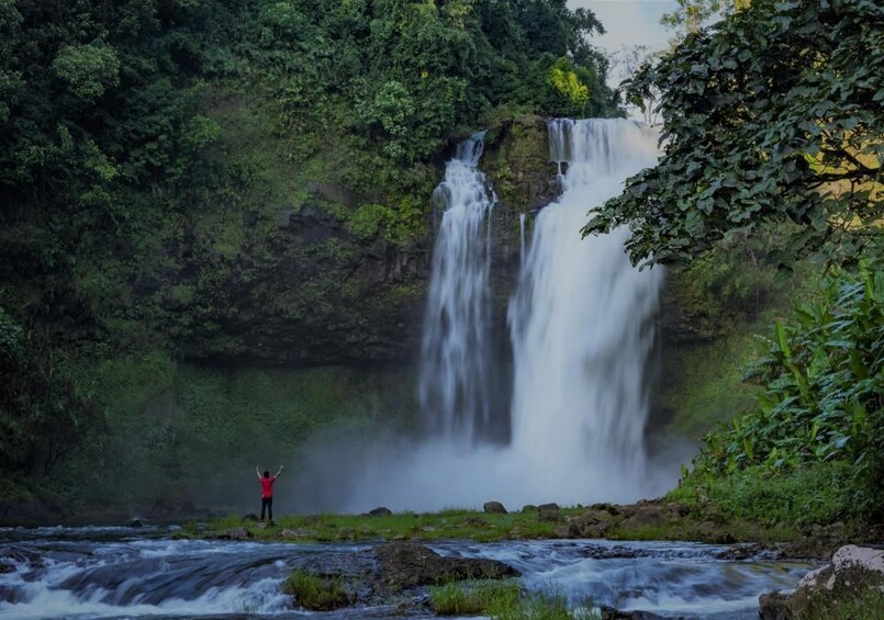 Person stands in front of Champi Waterfall in Paksong, Laos