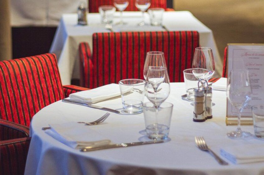 A restaurant setting with tables set for dining, chairs, and wine glasses. 3