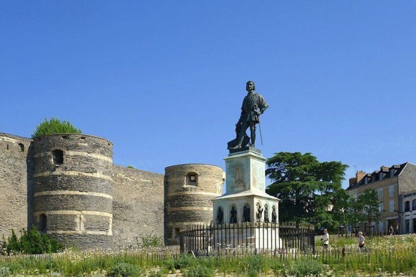 A statue on a pedestal, a stone wall, and a fence. 5