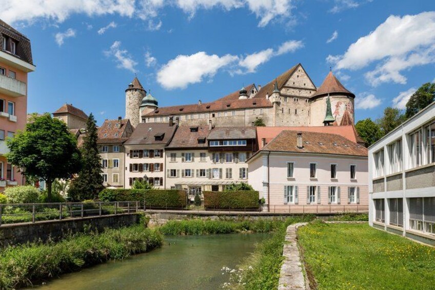 A historic building with a moat, surrounded by lush greenery and a clear sky. 4
