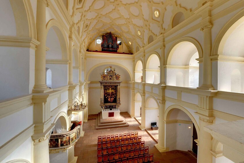 An ornate church interior with a high ceiling, arched windows, and a central altar. 5