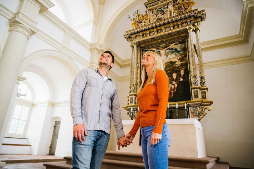 A couple holding hands in a church with ornate altars and high ceilings. 1