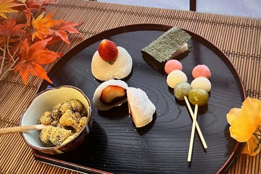 A traditional Japanese snack platter with various sweets and a bowl of mochi. 1