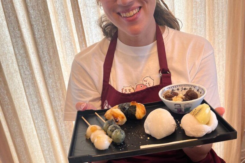 A person holding a tray with various food items, including sushi and dumplings. 3