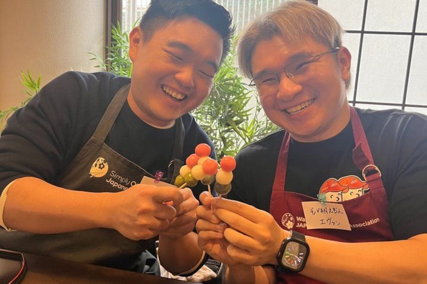 Two people wearing aprons with logos, holding a bunch of colorful items. 5