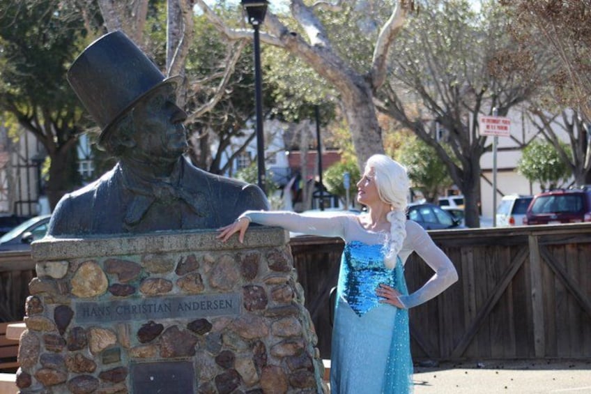 A statue of Hans Christian Andersen with a woman in a blue dress standing beside it. 1