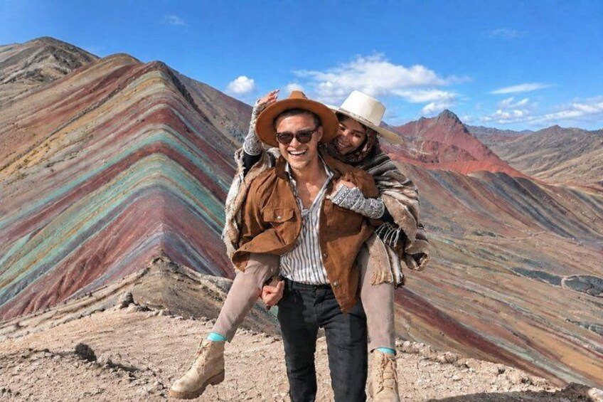 A person carrying another on their back against a colorful mountain backdrop. 3