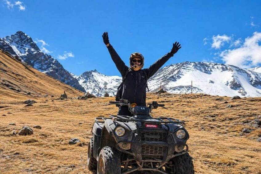 A person on a quad bike in a mountainous area with snow-capped peaks in the background. 5