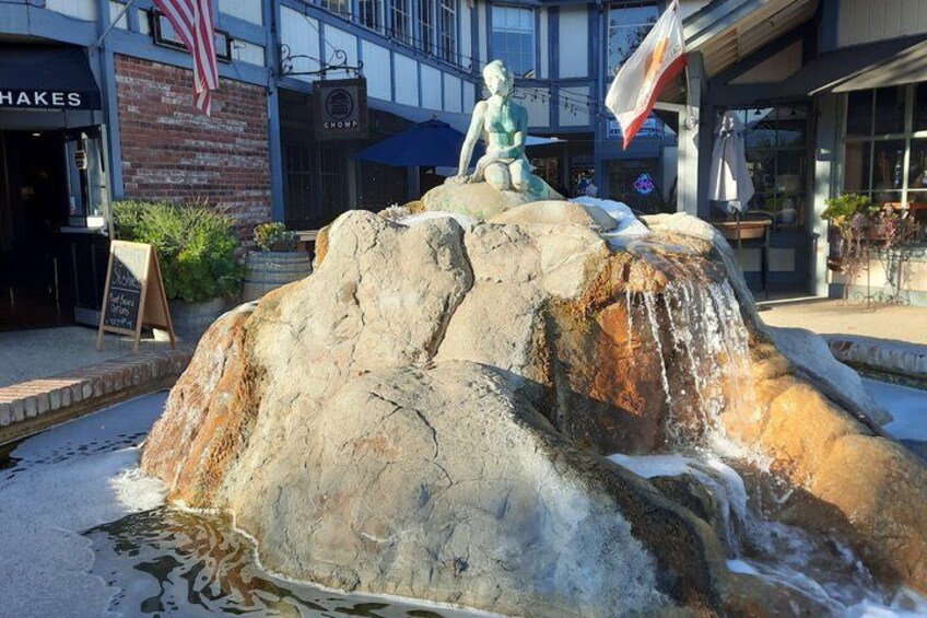 A rock formation with a statue on top, a small waterfall, and a signboard. 4