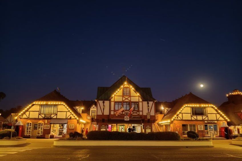 A traditional building with a thatched roof, illuminated by warm lights, and a clear night sky with a visible moon. 4