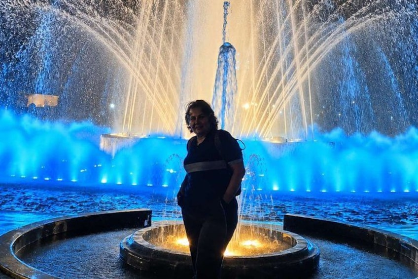 A person standing in front of a fountain with water jets and illuminated by blue lights. 3