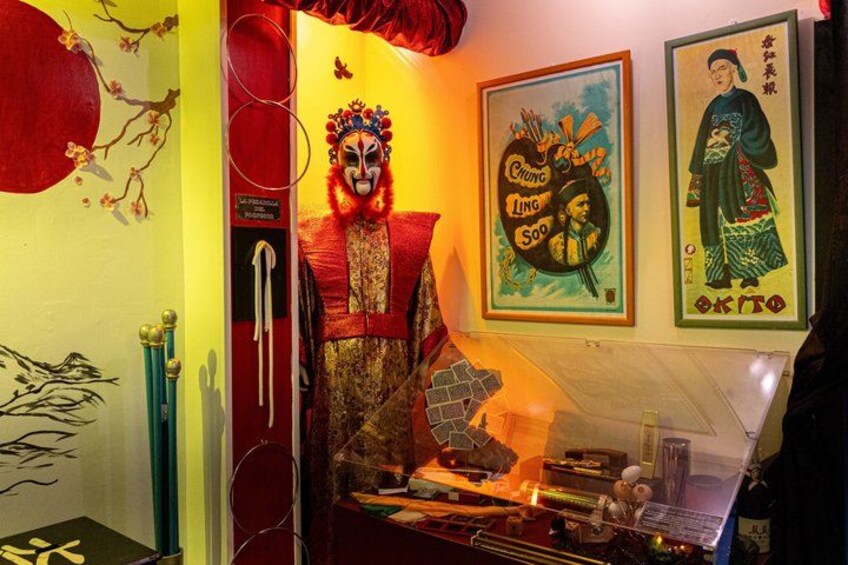 A traditional Chinese opera mask, a poster with Chinese characters, and a red curtain. 3