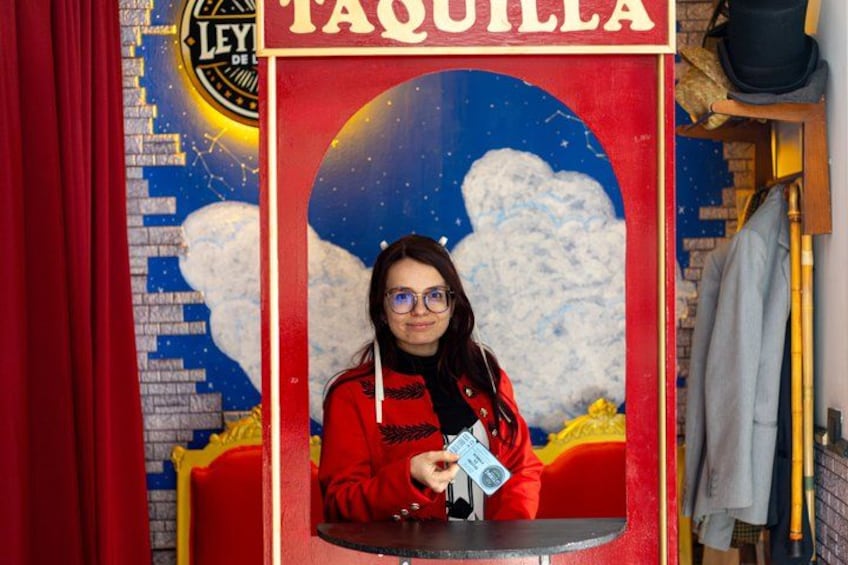 A person in a red jacket holding a camera in front of a 'TAQUILLA' sign. 2