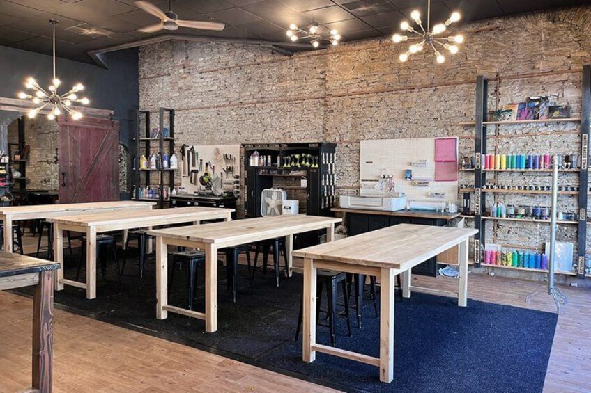 A workshop with wooden tables, a brick wall, and shelves with colorful items. 3