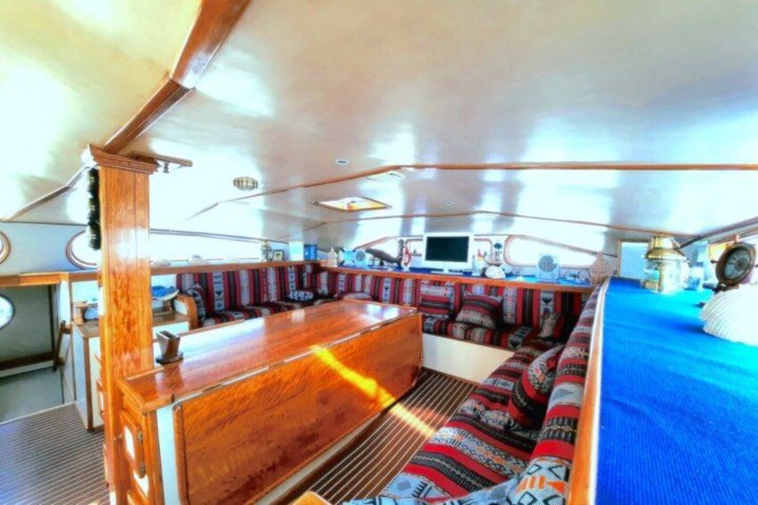 A boat's interior with a wooden bar, cushioned seating, and a blue area. 2