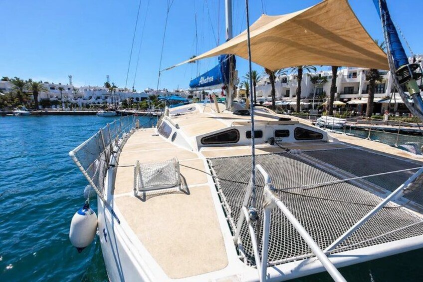 A sailboat docked at a marina with a clear blue sky and buildings in the background. 3