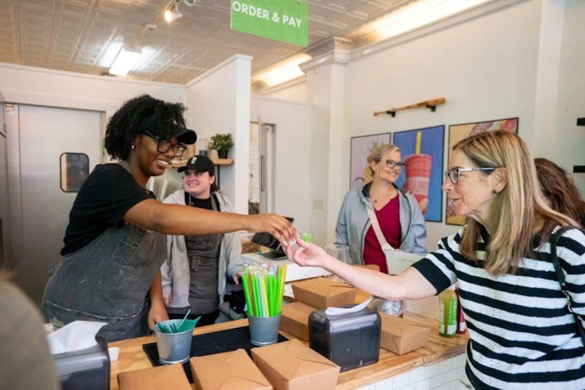 A person handing over a box to another person at a counter with a sign that reads 'ORDER & PAY'. 3