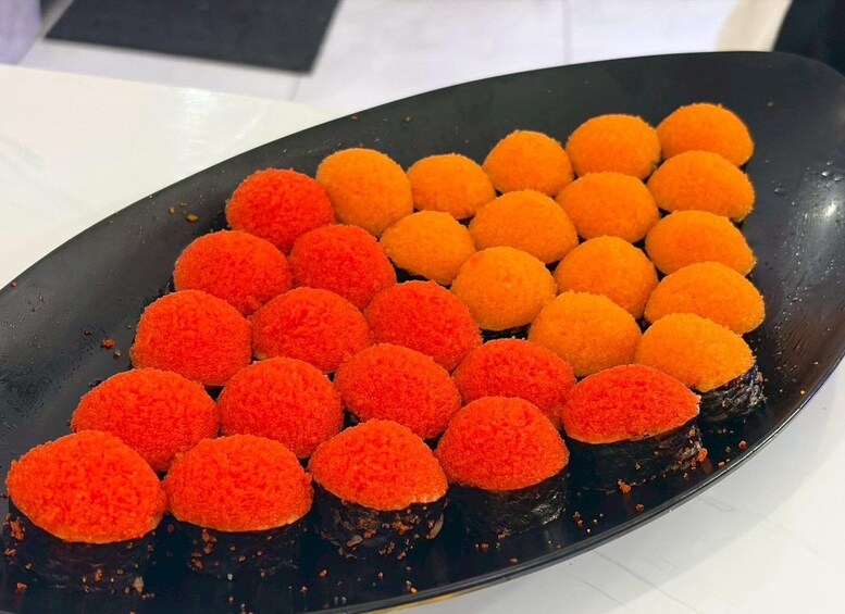 Ein Teller Sushi mit orangenen und roten Belägen. 5