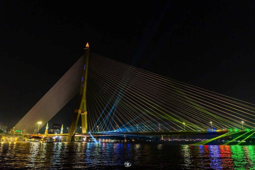 Ein Nachtbild einer Schrägseilbrücke mit beleuchteten Kabeln und einem zentralen Turm. 3