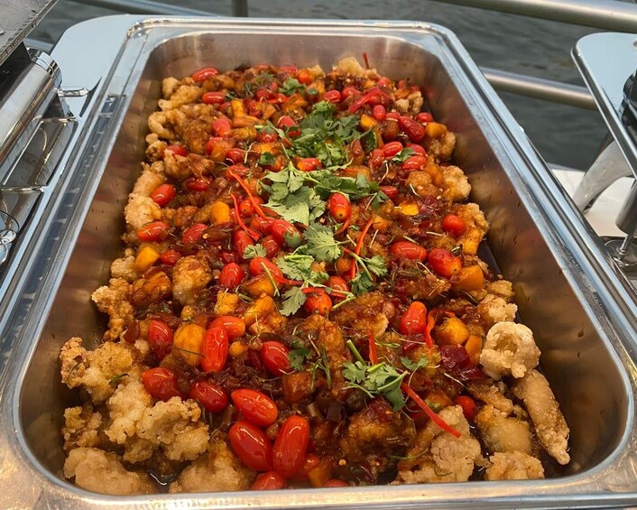 Ein Buffettablett mit gebratenem Hähnchen, Cocktailtomaten und Koriander-Garnitur. 2