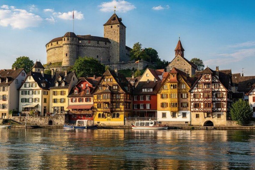 A historic town with colorful half-timbered houses, a castle, and a river. 4