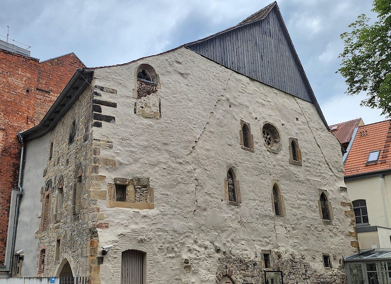 A historic building with a weathered facade, arched windows, and a steeply pitched roof. 3