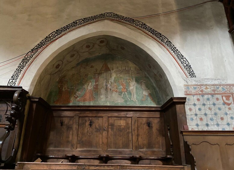 An arched wooden structure with a fresco mural above it. 5